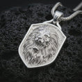 Load image into Gallery viewer, Polished silver roaring lion shield pendant necklace displayed on black volcanic rock, shown in a refined macro product shot with open mouth, fang detail, flowing mane, and angular shield frame.