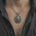 Load image into Gallery viewer, Oxidized lion medallion pendant necklace worn on the neck, styled in a dark lifestyle portrait with an open shirt and bold elegant presentation.