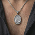 Load image into Gallery viewer, Polished silver Saint Benedict pendant necklace worn on the neck, shown against the chest in a clean and elegant everyday wear composition.