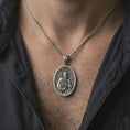 Load image into Gallery viewer, Oxidized Saint Peter pendant necklace worn on the neck, styled in a dark lifestyle portrait with an open shirt and masculine presentation.