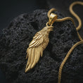 Load image into Gallery viewer, Gold plated raven pendant necklace presented on porous volcanic rock, highlighting the Norse-inspired bird design in a luxurious close-up jewelry image.