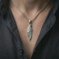 Load image into Gallery viewer, Polished silver raven pendant necklace worn on the neck, shown against the chest in a clean and striking everyday wear composition.