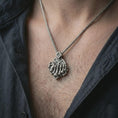 Load image into Gallery viewer, Oxidized chessboard pendant necklace worn on the neck, styled in a dark lifestyle portrait with an open shirt and bold intellectual presentation.