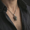 Load image into Gallery viewer, Oxidized gorilla head pendant necklace worn on the neck, styled in a dark lifestyle portrait with an open shirt and edgy urban presentation.