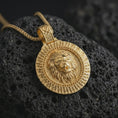Load image into Gallery viewer, Gold plated Viking lion medallion pendant necklace presented on porous volcanic rock, highlighting the Norse-inspired lion guardian motif in a luxurious close-up jewelry image.