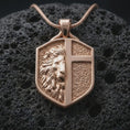 Load image into Gallery viewer, A rose gold plated shield pendant on volcanic rock featuring a lion emblem and cross motif in bold relief.