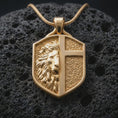 Load image into Gallery viewer, A gold plated lion cross shield pendant on black volcanic stone with crisp edges and textured background contrast.