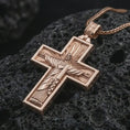 Load image into Gallery viewer, Rose gold plated Cristo Protetor cross pendant necklace on dark volcanic rock, photographed in a detailed premium studio macro view.