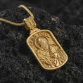 Load image into Gallery viewer, Gold plated Saint Paul dog tag pendant necklace presented on porous volcanic rock, highlighting the rectangular devotional form in a luxurious close-up jewelry image.