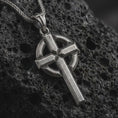 Load image into Gallery viewer, Sterling silver Celtic cross pendant necklace with an oxidized finish displayed on black volcanic stone, captured in a close-up studio image highlighting the bold cross form and circular halo detail.