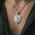 Load image into Gallery viewer, Polished silver Saint Michael pendant necklace worn on the neck, shown in a clean model shot with the shield-shaped religious pendant centered for a timeless devotional look.