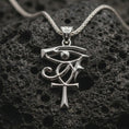 Load image into Gallery viewer, Polished silver Eye of Ra and Ankh pendant necklace displayed on black volcanic rock, shown in a refined macro product shot with ancient Egyptian symbol detail.