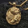Load image into Gallery viewer, Gold plated howling wolf pendant necklace presented on porous volcanic rock, highlighting the oval wilderness design in a luxurious close-up jewelry image.