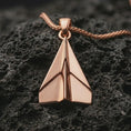 Load image into Gallery viewer, Rose gold plated origami airplane pendant necklace on dark volcanic rock, photographed in a detailed premium studio macro view.