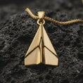Load image into Gallery viewer, Gold plated origami airplane pendant necklace presented on porous volcanic rock, highlighting the minimalist folded aircraft silhouette in a luxurious close-up jewelry image.