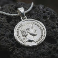 Load image into Gallery viewer, Polished silver Roman coin pendant necklace displayed on dark volcanic rock, shown in a premium close-up image that highlights the classical emperor portrait and worn ancient coin texture.