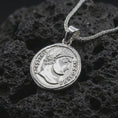 Load image into Gallery viewer, Polished silver Emperor Constans coin pendant necklace displayed on dark volcanic rock, shown in a premium close-up image that highlights the classical emperor portrait and ancient Roman coin texture.