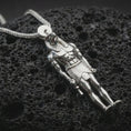 Load image into Gallery viewer, Polished silver Ra amulet pendant necklace displayed on dark volcanic rock, shown in a premium close-up image that highlights the Egyptian god figure, muscular relief, and elongated ceremonial silhouette.