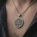 Load image into Gallery viewer, Oxidized Eye of Providence pendant necklace worn on the neck, styled in a dark lifestyle portrait with an open shirt and masculine presentation.