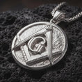 Load image into Gallery viewer, Polished silver Masonic emblem pendant necklace displayed on black volcanic rock, shown in a refined macro product shot with square and compass detail.