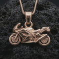 Load image into Gallery viewer, Rose gold plated sportbike motorcycle pendant necklace on dark volcanic rock, photographed in a detailed premium studio macro view.