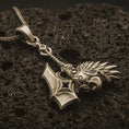 Load image into Gallery viewer, Bronze paladin hammer pendant necklace with an oxidized finish resting on textured volcanic rock, captured in a close-up premium studio composition.
