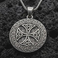 Load image into Gallery viewer, Sterling silver Celtic knot medallion necklace with an oxidized finish resting on textured volcanic rock, captured in a close-up premium studio composition.