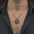 Load image into Gallery viewer, Oxidized samurai skull pendant necklace worn on the neck, styled in a dark lifestyle portrait with an open shirt and masculine presentation.