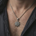 Load image into Gallery viewer, Oxidized Eye of Providence sun pendant necklace worn on the neck, styled in a dark lifestyle portrait with an open shirt and masculine presentation.