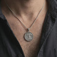 Load image into Gallery viewer, Oxidized Venus Amor pendant necklace worn on the neck, styled in a dark lifestyle portrait with an open shirt and artistic presentation.