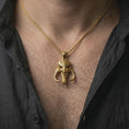 Load image into Gallery viewer, Gold plated Mythosaur skull pendant necklace worn on the neck, captured on a human model in a premium dark-toned lifestyle frame.
