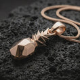 Load image into Gallery viewer, Rose gold plated origami pineapple pendant necklace on dark volcanic rock, photographed in a detailed premium studio macro view.