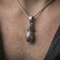 Load image into Gallery viewer, Oxidized origami pineapple pendant necklace worn on the neck, styled in a dark lifestyle portrait with an open shirt and modern presentation.