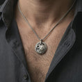 Load image into Gallery viewer, Oxidized Spartan warrior pendant necklace worn on the neck, styled in a dark lifestyle portrait with an open shirt and masculine presentation.