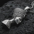 Load image into Gallery viewer, Sterling silver Nefertiti pendant necklace with an oxidized finish resting on textured volcanic rock, captured in a close-up premium studio composition.