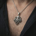 Load image into Gallery viewer, Oxidized octopus pendant necklace worn on the neck, styled in a dark lifestyle portrait with an open shirt and bold ocean-inspired presentation.