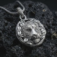 Load image into Gallery viewer, A polished 925 sterling silver tiger pendant on volcanic rock showing crisp facial relief, smooth shine, and wreath detail.