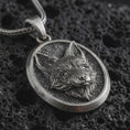 Load image into Gallery viewer, Sterling silver fox medallion pendant necklace with an oxidized finish resting on textured volcanic rock, captured in a close-up premium studio composition.