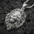 Load image into Gallery viewer, Polished silver lion head pendant necklace displayed on black volcanic rock, shown in a refined macro product shot with realistic facial sculpting, flowing mane detail, and bold wildlife character.