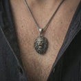 Load image into Gallery viewer, Oxidized roaring lion head pendant necklace worn on the neck, styled in a dark lifestyle portrait with an open shirt and bold masculine presentation.