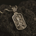 Load image into Gallery viewer, Bronze Joan of Arc dog tag pendant necklace resting on black volcanic stone, featuring a detailed saint warrior portrait with halo, folded hands, and armor in a devotional sterling silver design.