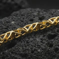Load image into Gallery viewer, Gold plated DNA helix chain necklace presented on porous volcanic rock, highlighting the geometric double-helix inspired link pattern in a luxurious close-up jewelry image.