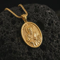 Load image into Gallery viewer, Gold plated Saint Paul pendant necklace on textured volcanic rock, premium close-up studio composition emphasizing the apostle figure, sword, and book symbolism.