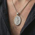 Load image into Gallery viewer, Polished silver Saint Roch pendant necklace worn on the chest, masculine lifestyle shot highlighting the saint relief, pilgrim staff, dog detail, and bright silver finish.
