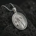 Load image into Gallery viewer, Polished silver spinning Good Shepherd pendant necklace on textured volcanic rock, centered macro jewelry photo with detailed shepherd relief and bright silver highlights.