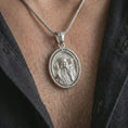 Load image into Gallery viewer, Polished silver spinning Good Shepherd pendant necklace worn on the chest, masculine lifestyle shot highlighting the Jesus and lamb relief with bright silver finish.