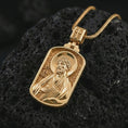 Load image into Gallery viewer, Gold plated Saint James the Apostle pendant necklace on textured volcanic rock, premium close-up studio composition emphasizing the apostle figure, halo, and sacred book symbolism.