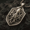 Load image into Gallery viewer, Bronze kraken octopus shield pendant necklace with an oxidized finish resting on textured volcanic rock, captured in a close-up premium studio composition.