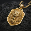 Load image into Gallery viewer, Gold plated roaring lion shield pendant necklace presented on porous volcanic rock, highlighting the fierce warrior-inspired lion motif in a luxurious close-up jewelry image.