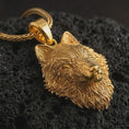 Load image into Gallery viewer, Gold plated wolf head pendant necklace presented on porous volcanic rock, highlighting the fierce woodland predator motif in a luxurious close-up jewelry image.